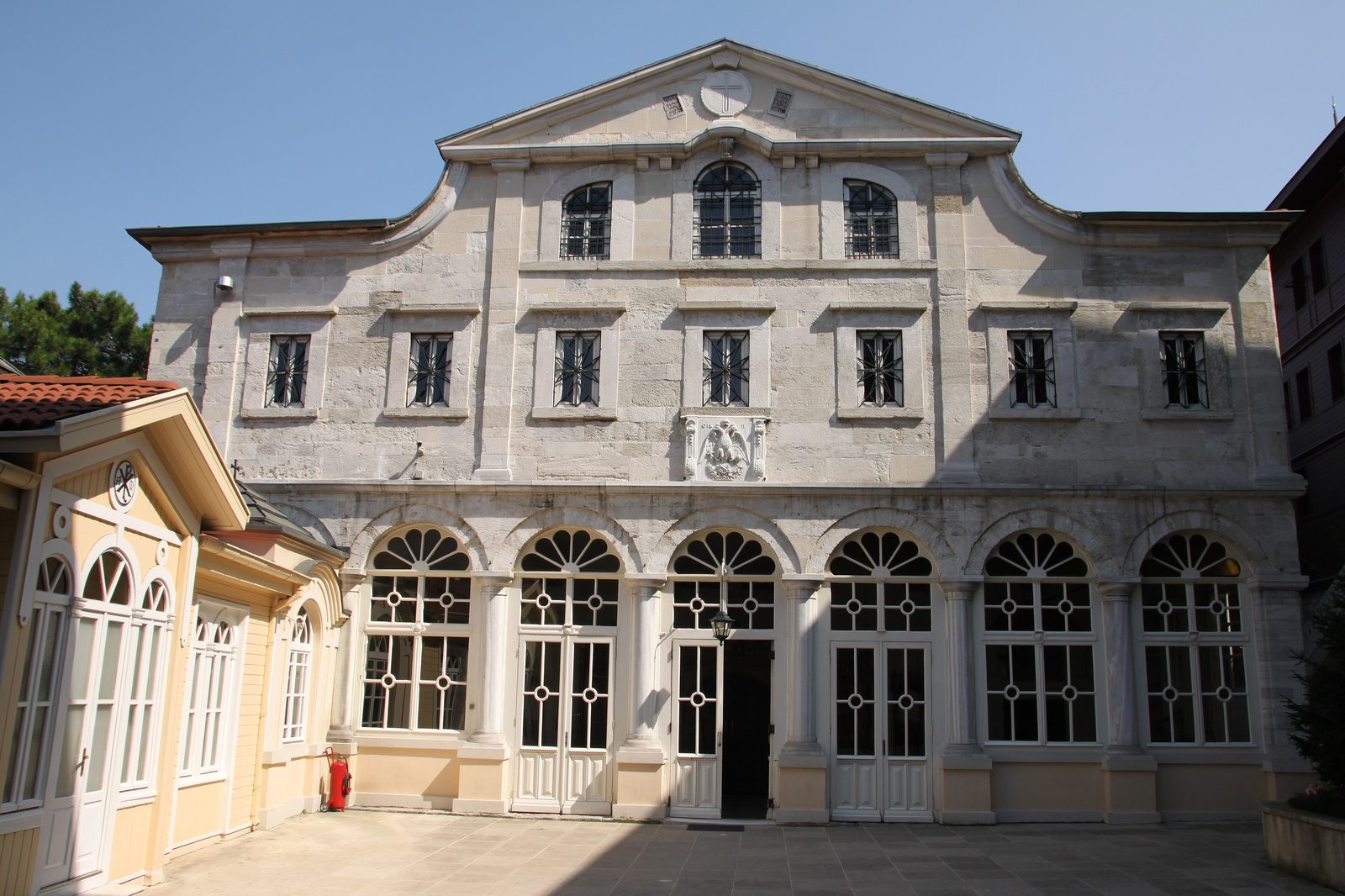 The neoclassical stone facade of the Church of St. George, the Patriarchal Cathedral of the Greek Orthodox Patriarchate in Fener, with arched windows and a relief of St. George above the central doors