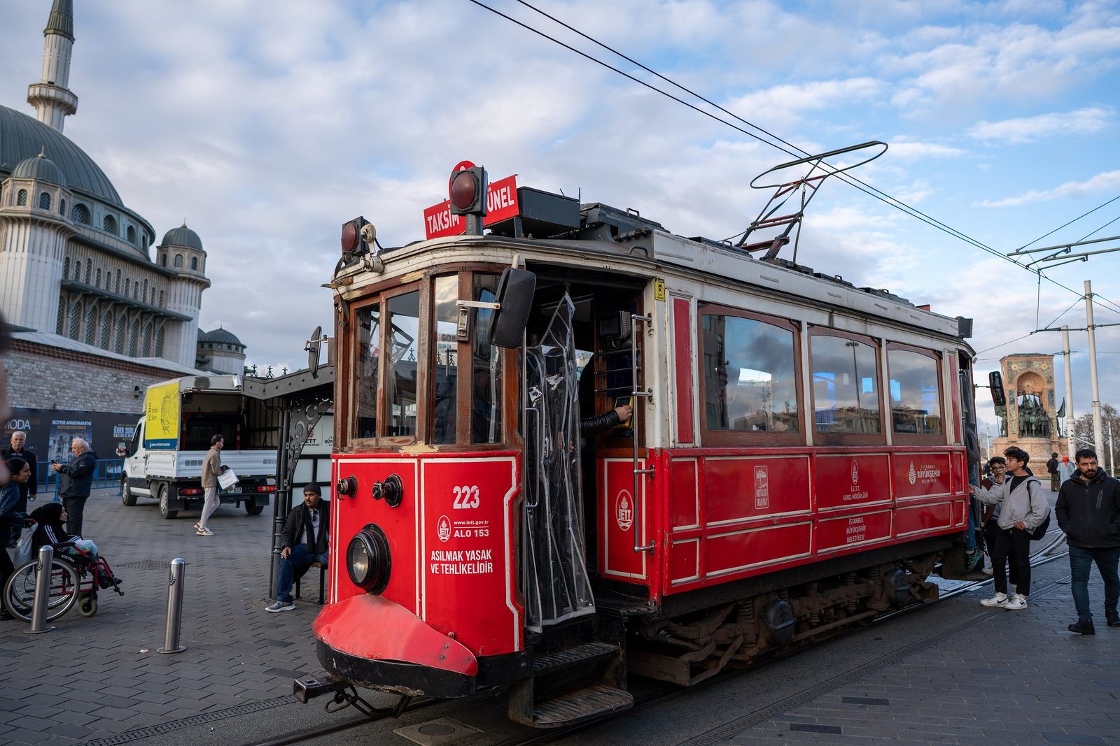 The historic red nostalgic tram on İstiklal Caddesi in Beyoğlu, with shopfronts and pedestrians along the pedestrianised boulevard