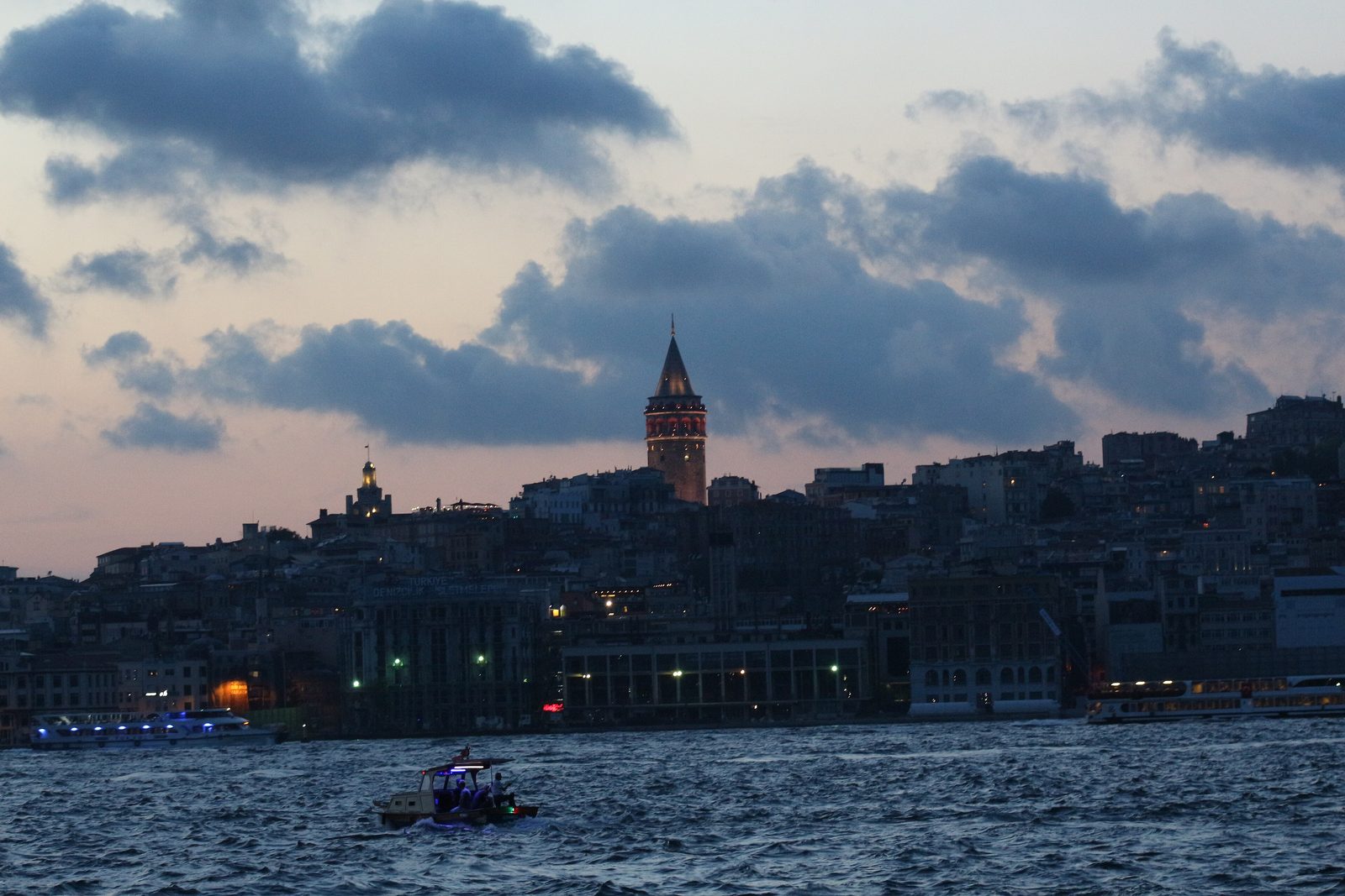 The Galata Tower in Karaköy seen at evening — the 14th-century stone watchtower with its conical roof, lit against a darkening sky